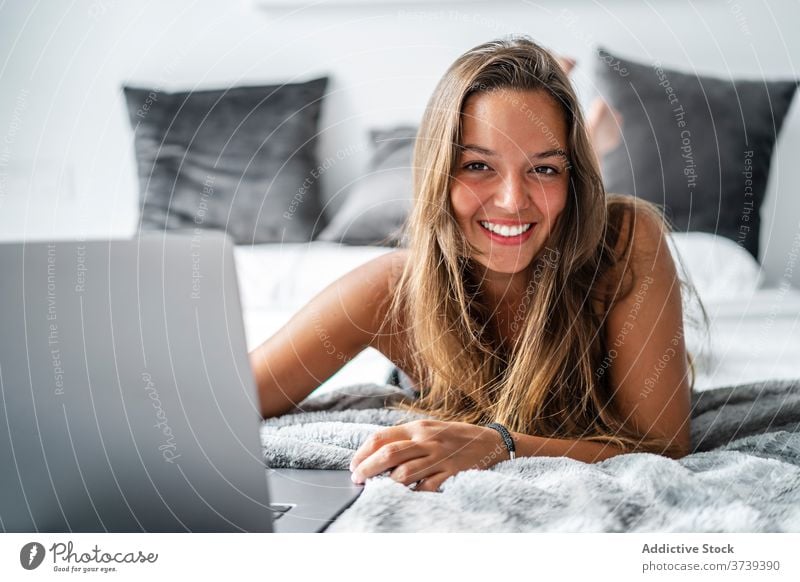 Fröhliche Frau mit Laptop auf dem Bett Morgen genießen benutzend Talkrunde Nachtwäsche Komfort Tippen heimwärts gemütlich Lügen Internet Apparatur online