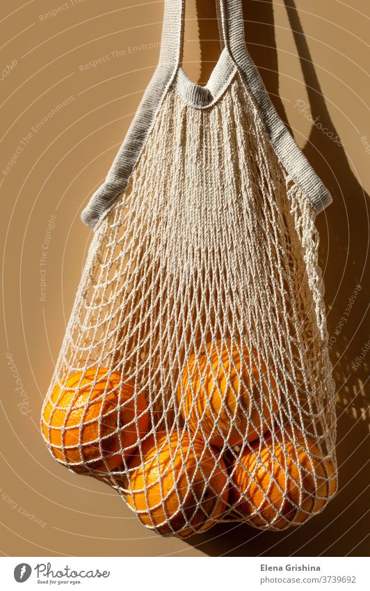 Reife Orangen in einem weißen Schnurbeutel. Beigefarbener Hintergrund. keine Verschwendung Öko kaufen orange Tasche beige wiederverwendbar Konzept Ökologie