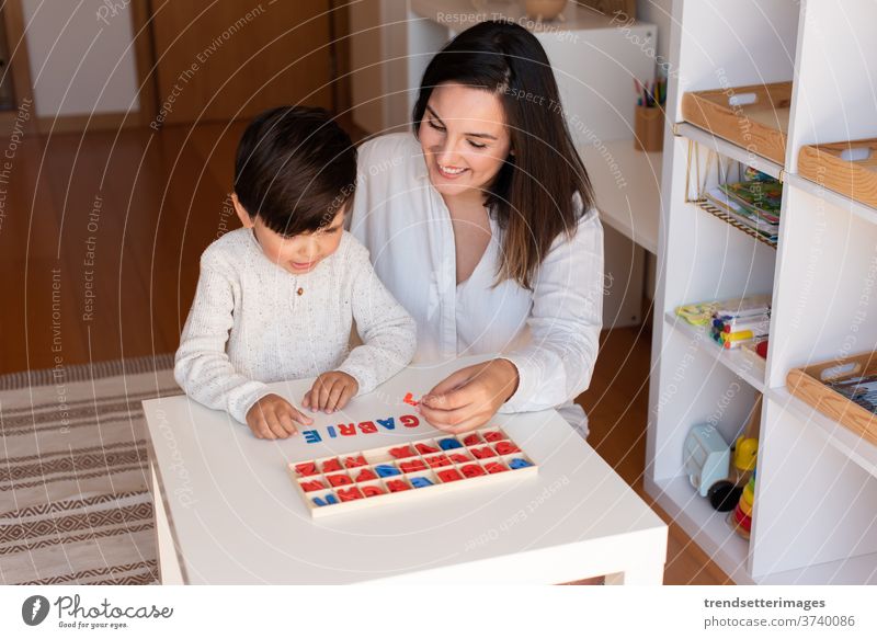 Das Kind lernt mit Hilfe eines Alphabets und der Mutter oder des Lehrers schreiben und lesen. Hausunterricht. Lernende Gemeinschaft. Montessori-Schule Briefe