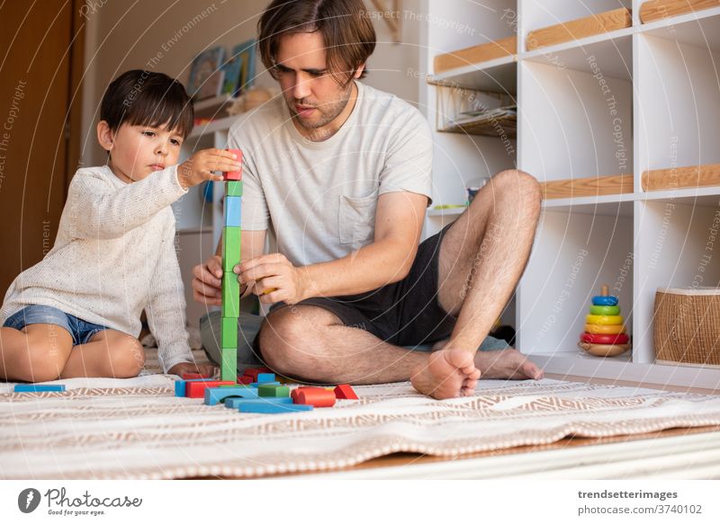 Kind und sein Vater spielen zu Hause mit Holzbausteinen. Heimunterricht. Bleiben Sie zu Hause. Zeit mit der Familie covid-19 sicher Coronavirus zu Hause bleiben