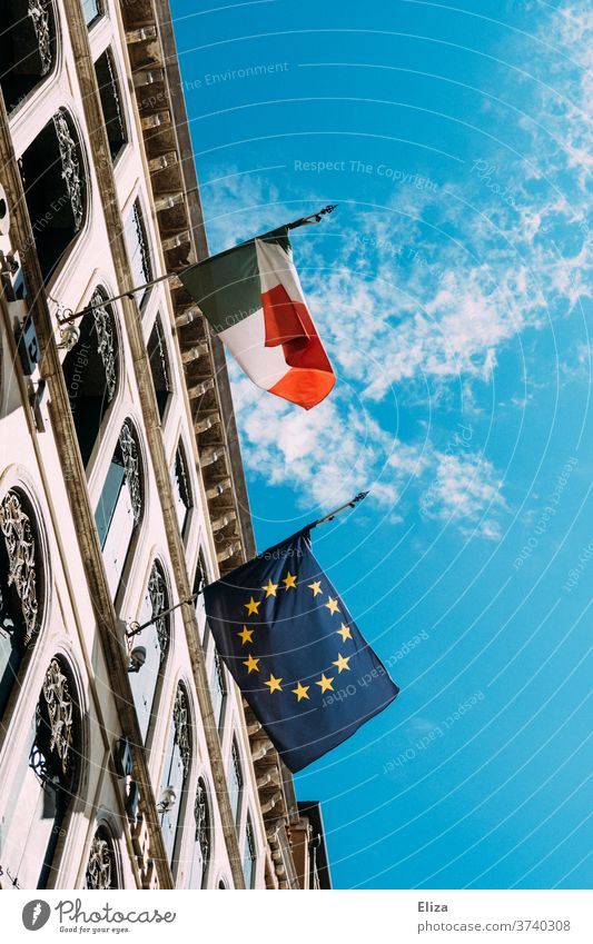 Eine italienische und eine europäische Flagge hängen nebeneinander an einem Gebäude und flattern im Wind Italien Europa Europaflagge gehisst Himmel Fahne