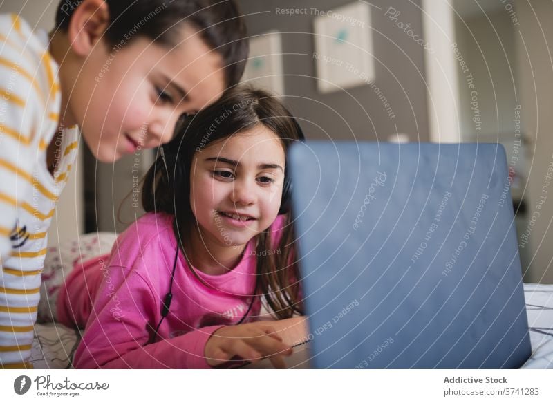 Fröhliche Kinder mit Laptop im Schlafzimmer Schwester und Bruder benutzend heimwärts Geschwisterkind Zusammensein wenig Apparatur heiter spielen Glück