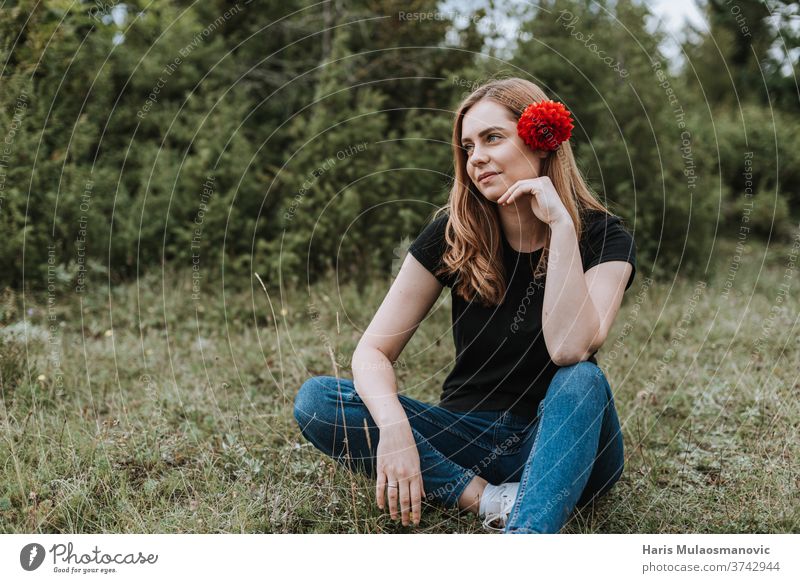 Junge schöne Frau mit Blume im Haar sitzt in der Natur attraktiv Hintergrund Schönheit blond Kaukasier niedlich Mode Behaarung Fröhlichkeit Glück Lifestyle