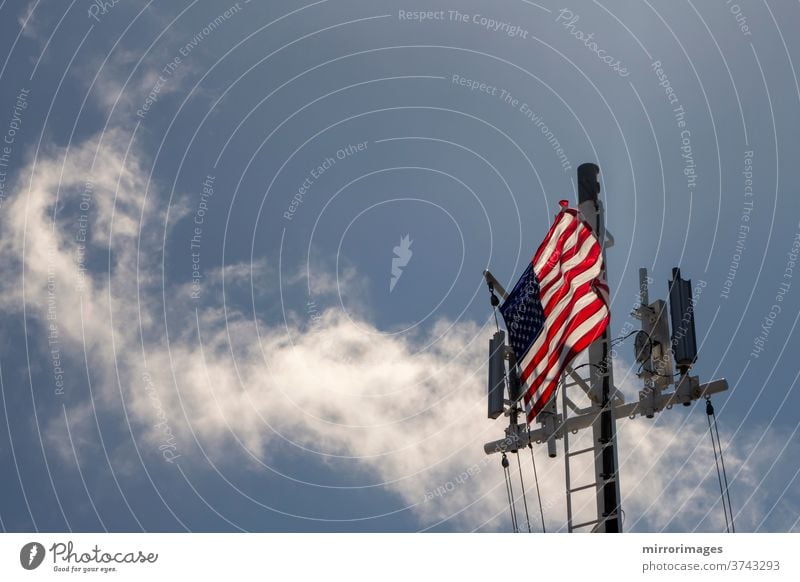 Die Flagge der Vereinigten Staaten von Amerika weht im Wind auf dem Deck eines großen Schiffes auf See mit Mobilfunkmasten amerika Amerikaner Transparente
