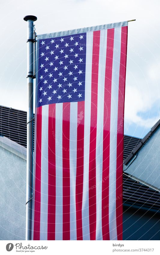 US-amerikanische Nationalflagge vor einem Gebäude. USA Flagge Fahne Amerika Stars and Stripes Fahnenmast formatfüllend Patriotismus Himmel Haus Streifen Sterne