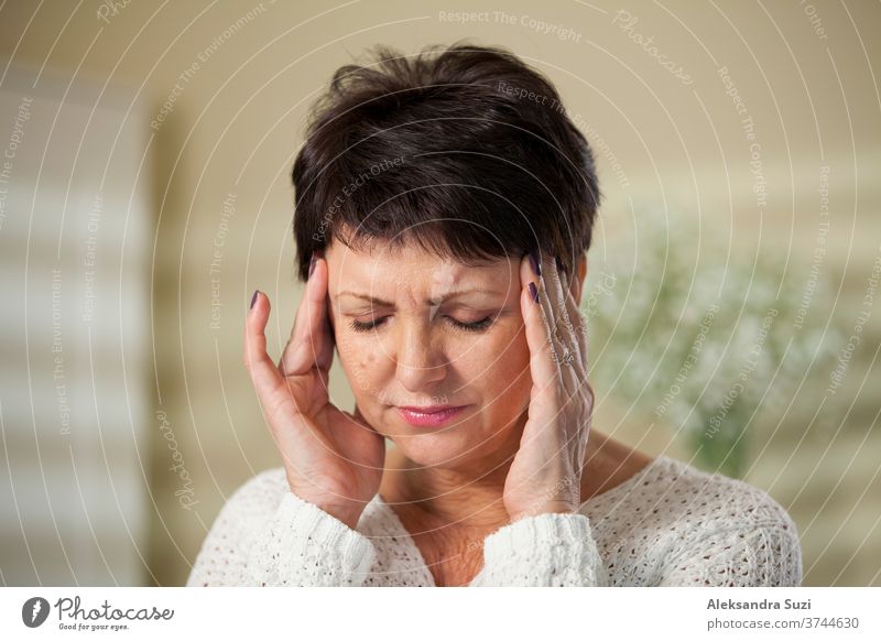 Attraktive reife Frau mit Kopfschmerzen. Hände an den Schläfen. Druck Krankheit Migräne Erwachsener Mitte deprimiert lässig alt Reife Gesicht Massage Gesundheit