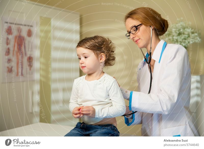 Süßes kleines Mädchen und Arzt. Kinderärztin, die ein süßes kleines Mädchen mit einem Stethoskop untersucht. Das Kind sieht gesund und glücklich aus Baby