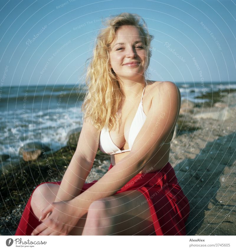 Analoges Portrait einer jungen Frau im Bikini am Ostseestrand Gischt Wellen Meer rot Strand heiß schönes Wetter Abendlicht Sonnenlicht selbstbewußt feminin