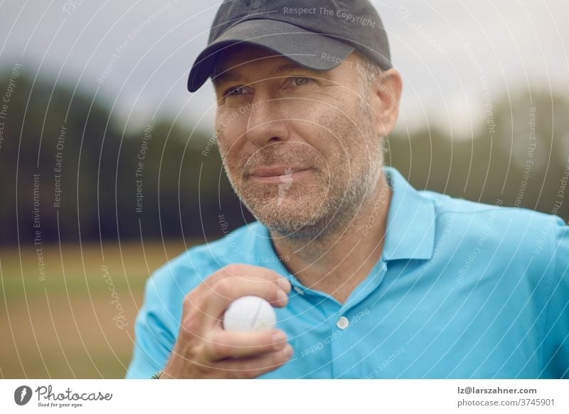 Männlicher Golfer mittleren Alters, der in einem Nahaufnahmeausschnitt seinen Schlag betrachtet und mit einem Golfball in der Hand das Fairway hinunterblickt