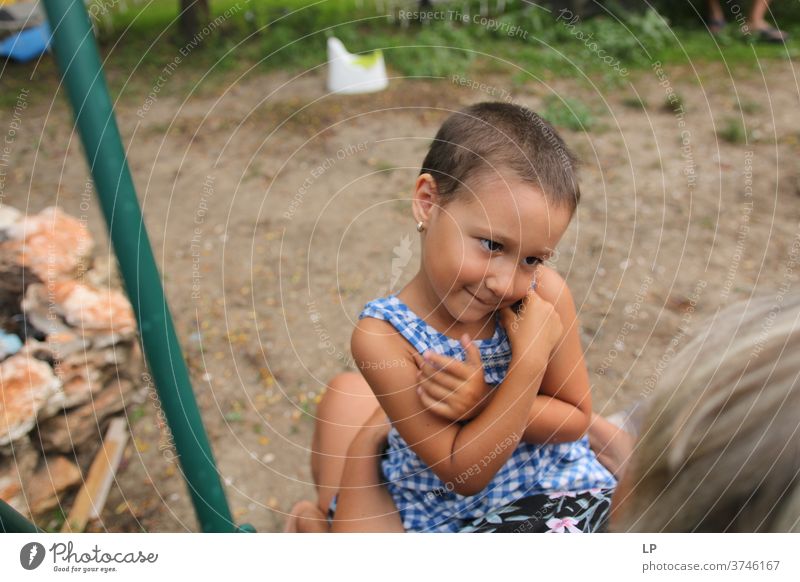 kleines Mädchen, das die Arme auf der Brust hält und einen Erwachsenen anschaut und anlächelt Arme hoch Schutz Körpersprache Mensch Gefühle Kommunizieren