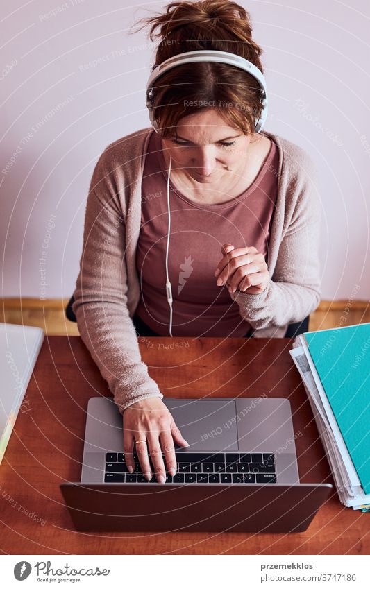 Frau, die während eines Videochat-Telefongesprächs mit einem Laptop von zu Hause aus arbeitet und dabei ihre Arbeit aus der Ferne erledigt Ordner Anruf