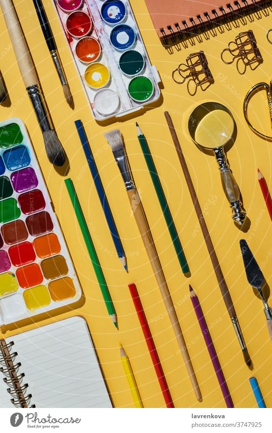 Flachlegung von Aquarellen, Pinseln, Notizbüchern und anderen Schreibwaren und Kunstgegenständen auf Gelb blanko Business farbenfroh kreativ Designer