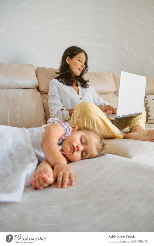 Kleinkind schlafend, während ihre Mutter mit einem Laptop arbeitet Mutterschaft Zärtlichkeit Ruhe Sofa Verantwortung neugeboren Unschuld friedlich Drahtlos
