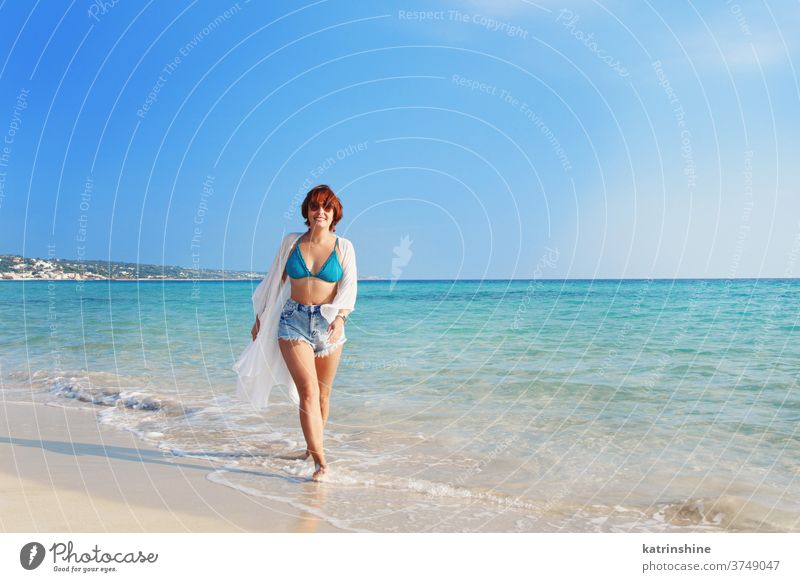 Junge Frau in Bedeckung und Jeans-Shorts am Strand spazieren jung zudecken Kimono weiß blau türkis Jeanshose laufen hohe Taille reisen Ferien Konzept