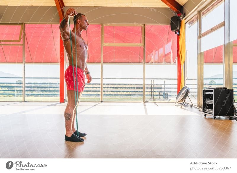 Starker Mann trainiert in heller Turnhalle widersetzen Band Übung Athlet Fitnessstudio Training muskulös elastisch männlich Zentrum modern Kraft Gesundheit
