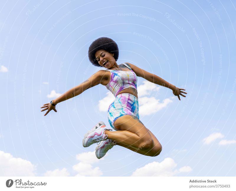 Fröhliche schwarze Frau springt gegen den Himmel springen Freude Spaß haben Moment aufgeregt heiter ausdehnen Sommer ethnisch Afroamerikaner Frisur Afro-Look