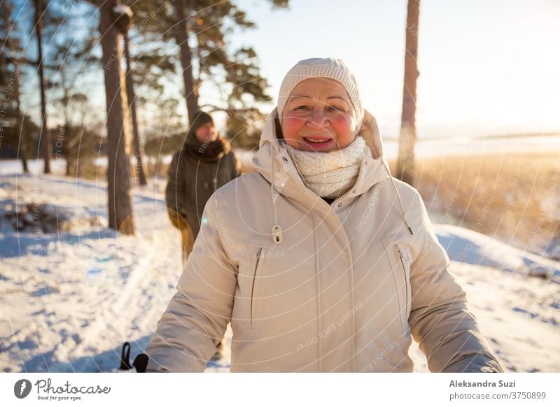 Wintersport in Finnland - Nordic Walking. Ältere Frau und Mann beim Wandern im kalten Wald. Aktive Menschen im Freien. Malerisch ruhige finnische Landschaft.