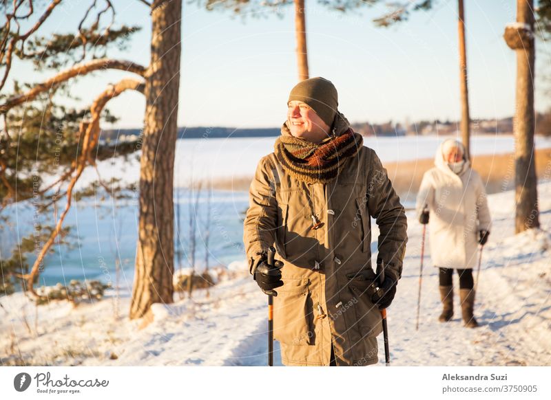 Wintersport in Finnland - Nordic Walking. Mann und ältere Frau beim Wandern im kalten Wald. Aktive Menschen im Freien. Malerisch ruhige finnische Landschaft mit Schnee.