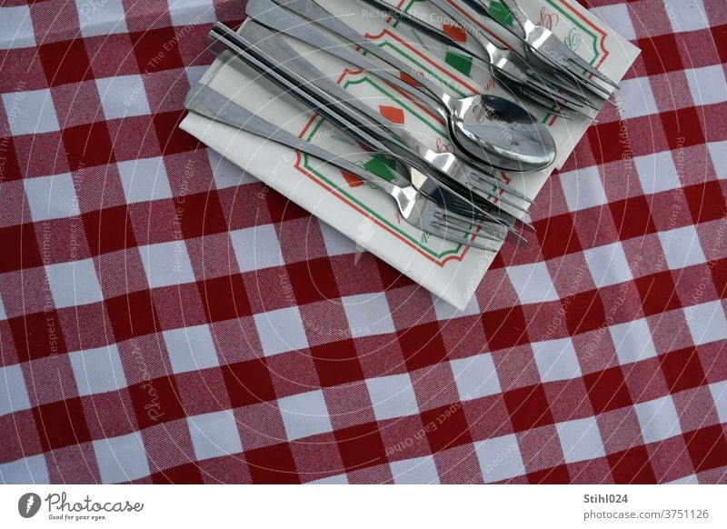 Besteck liegt auf Serviette auf rot-weiß karierter Tischdecke Restaurant coperto Gedeck Draufsicht italienisch Pizzeria Messer GAbel Löffel Set Essen Mahlzeit