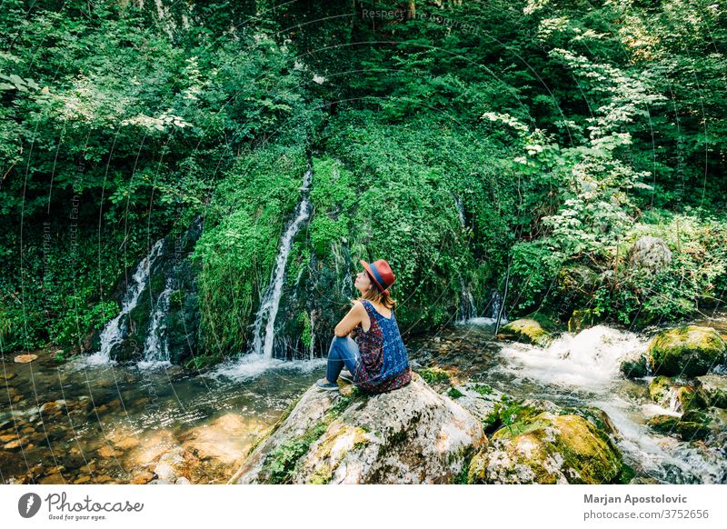 Junge weibliche Naturforscherin geniesst an den Wasserfällen Abenteuer schön Kaskade lässig Kaukasier entdecken Fundstück genießen erkunden Frau fließen