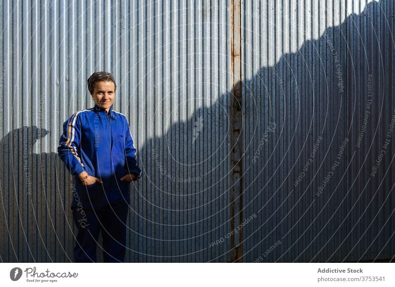 Lächelnde Frau in Arbeitskleidung auf dem Bauernhof Arbeiter Uniform Gebäude ländlich Sonnenlicht Metall Wand stehen heiter Mitarbeiter positiv freundlich