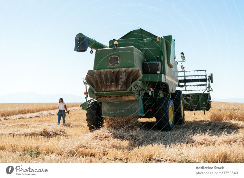 Frau in der Nähe von Mähdrescher im Feld Ernte Maschine Ackerbau Weizen Landwirt Gerät Korn Industrie ländlich riesig Natur Sommer Pflanze organisch Wachstum