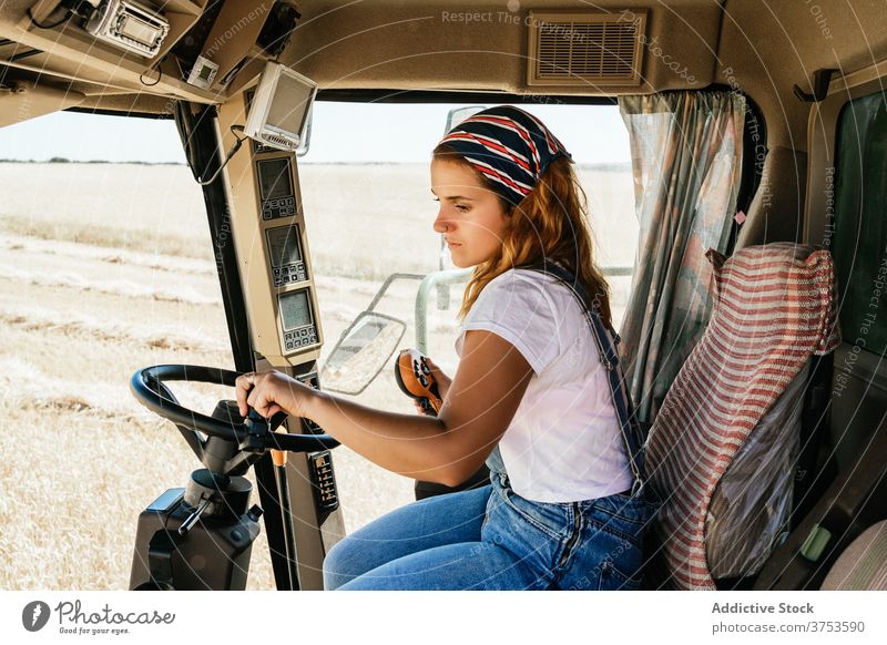 Fokussierte Frau bei der Bedienung einer landwirtschaftlichen Maschine Bauernhof Mähdrescher Ernte arbeiten abholen Saison Feld Ackerbau Weizen ländlich Job
