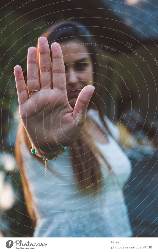 Eine junge Frau symbolisiert Stopp indem sie ihre Hand vor sich ausstreckt. Nein heißt Nein. Halt wehrhaft Ablehnung Gefühle Signal Kommunikation wehren