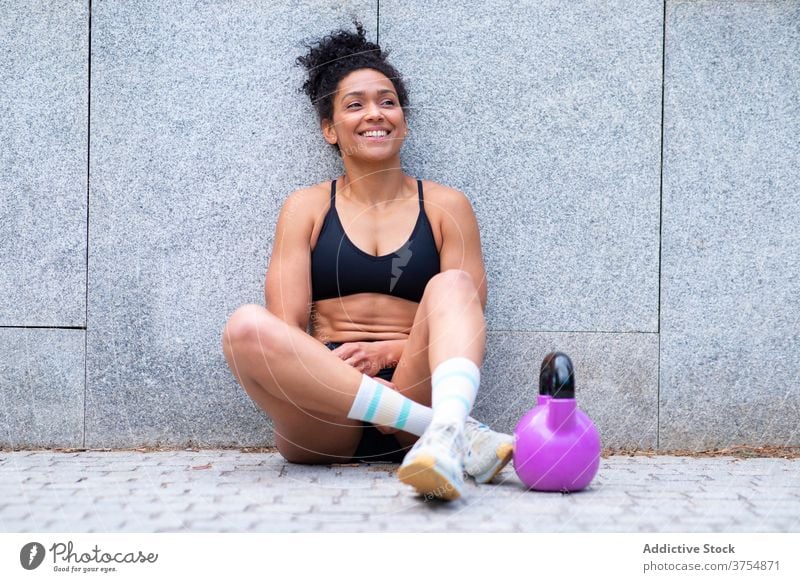 Inhalt ethnische Sportlerin ruht sich während des Trainings aus operativ sich[Akk] entspannen Pause Großstadt Kettlebell Lächeln passen Frau schwarz