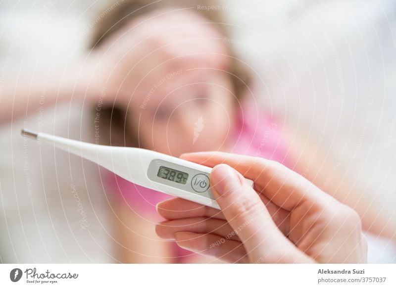 Nahbereichsthermometer. Mutter misst die Temperatur ihres kranken Kindes. Krankes Kind mit hohem Fieber im Bett liegend und Mutter hält Thermometer. Hand auf der Stirn.