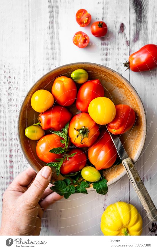 Hand mit einem Teller voller roher Tomaten auf einem Holztisch. Draufsicht, gesunde Ernärhung. rot halten Messer Gemüse Farbfoto Ernährung Gesunde Ernährung