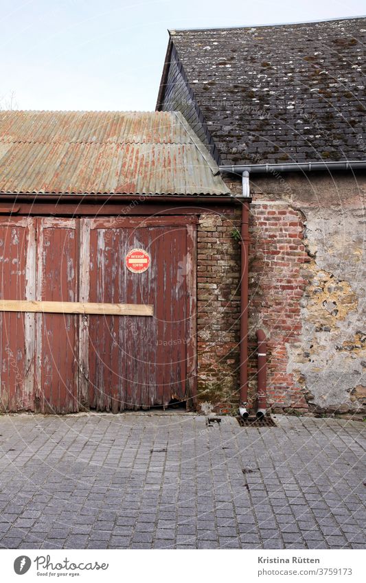 altes haus trifft auf alte garage mit französischem parken verboten schild scheune schuppen hof einfahrt zufahrt garagenausfahrt freihalten holztor garagentor