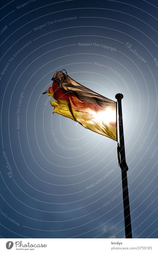 wehende , leuchtende Deutschlandflagge mit durchscheinender Sonne leuchtet im Gegenlicht vor wolkenlosem Himmel. Deutschlandfahne, schwarz-rot gold