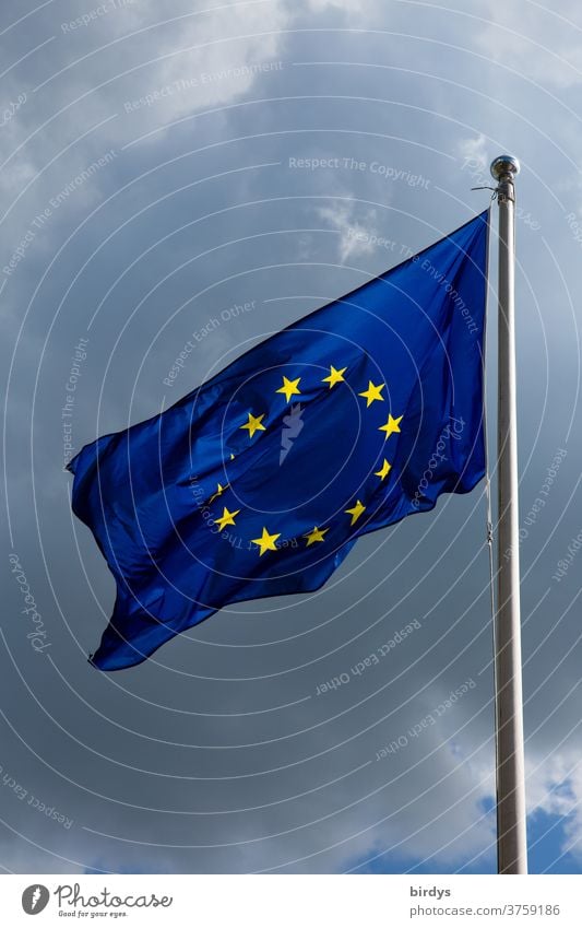 Europaflagge , Fahne der Europäischen Union weht im Wind . Gewitterwolken im Hintergrund Europäische Union Europafahne wehende Fahne blau gelbe Sterne
