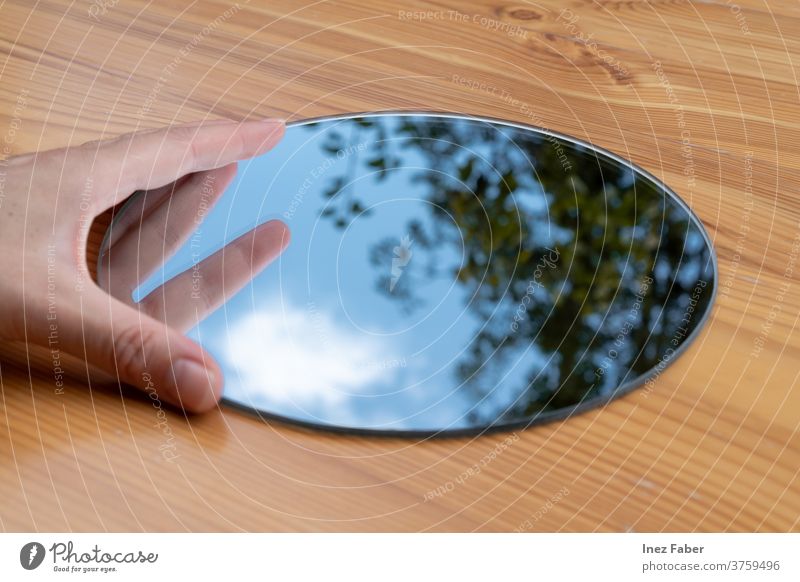 Runder Handspiegel auf einem Tisch, Spiegelung eines Baumes, Wolken und blauer Himmel Windstille den Himmel einfangen Wolkenreflexion Cloud Baumreflexion