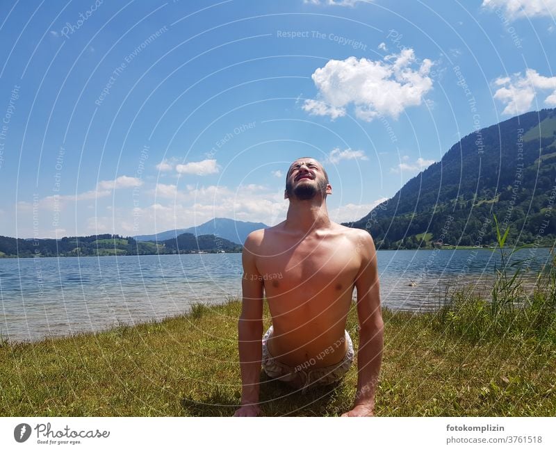junger Mann macht Körper Gymnastik an einem See Dehnungsübung Yoga Gesundheit Oberkörper Fitness Sport maskulin Sport-Training Sportler im Freien muskulös