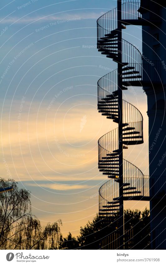 gewendelte Außentreppe an einem Gebäude vor schönem Abendhimmel. Wendeltreppe spiralförmig Spirale Geländer nach oben nach unten Architektur Wege & Pfade Treppe