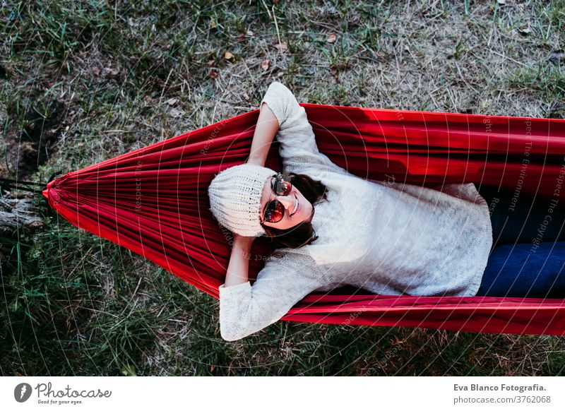 junge Frau entspannt sich in orangefarbener Hängematte. Zelten im Freien. Herbstsaison bei Sonnenuntergang Lügen Natur Park Kaukasier vorbereitend