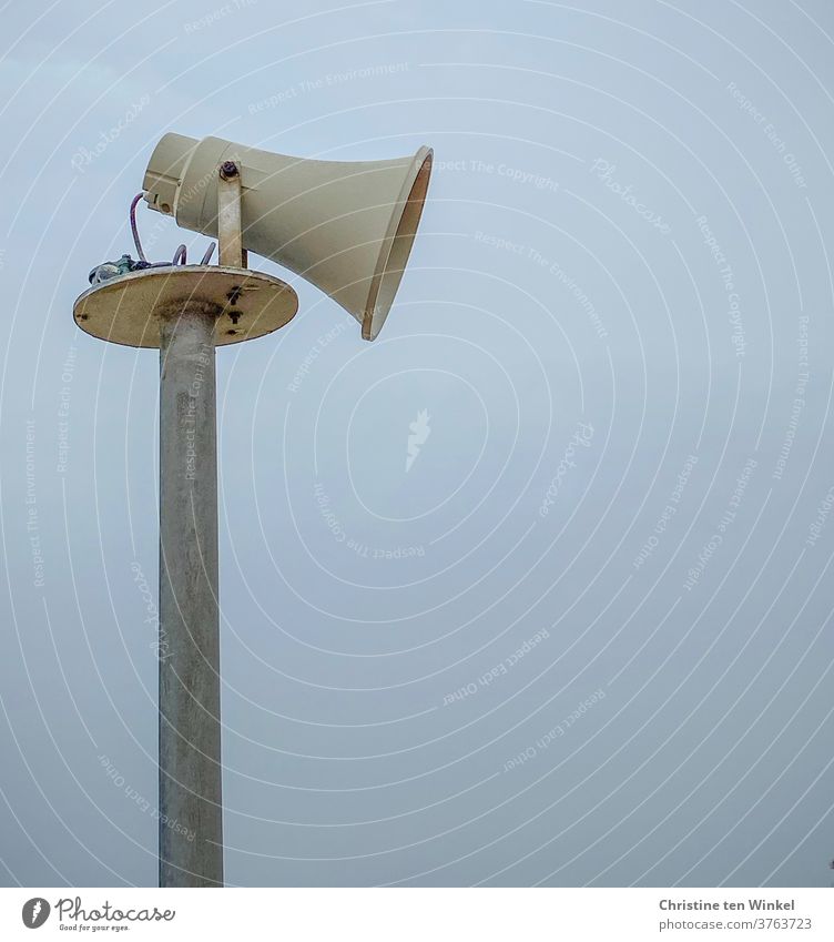 Seitenansicht eines älteren Lautsprechers in Form eines Megaphons vor bläulich diesigem Himmel Megafon Mast Durchsage Kommunizieren Information Warnung