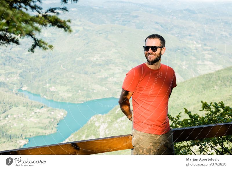 Junger Mann in den Bergen mit Blick auf den See Abenteuer allein Hintergrund schön Schlucht Kaukasier Tag Saum genießend erkunden Entdecker frei Freiheit Typ