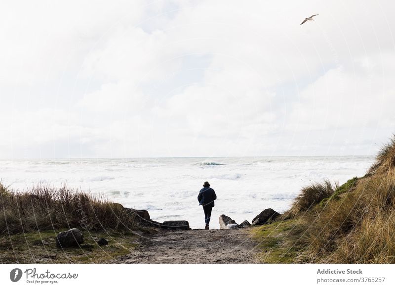 Unbekannter männlicher Reisender, der in Richtung Meer geht reisen Mann MEER Spaziergang stürmisch schäumen wolkig Strand Tourist USA Vereinigte Staaten amerika