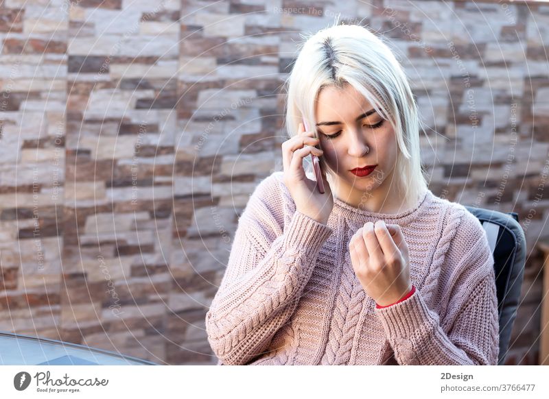 Glückliche blonde junge Frau sitzt im Freien und telefoniert mit ihrem Handy Mobile Person Erwachsener Telefon Mitteilung Technik & Technologie Lifestyle schön