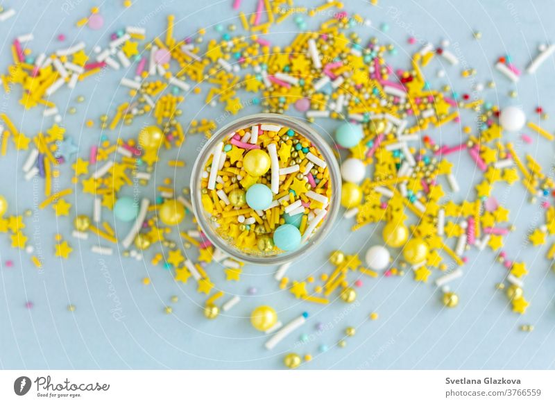 Gelbe Zuckerstreusel körnig auf blauem Hintergrund, Nahaufnahme flachgelegt farbenfroh Bonbon Farbe süß Lebensmittel Dessert Geburtstag Feiertag rosa Kuchen