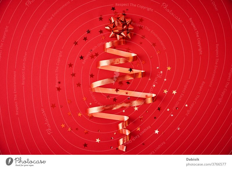Weihnachtsbaum aus festlichem Band und Konfetti auf rotem Hintergrund. Weihnachtsschmuck Weihnachten Dekoration & Verzierung Baum Bändchen Feiertag neu Jahr