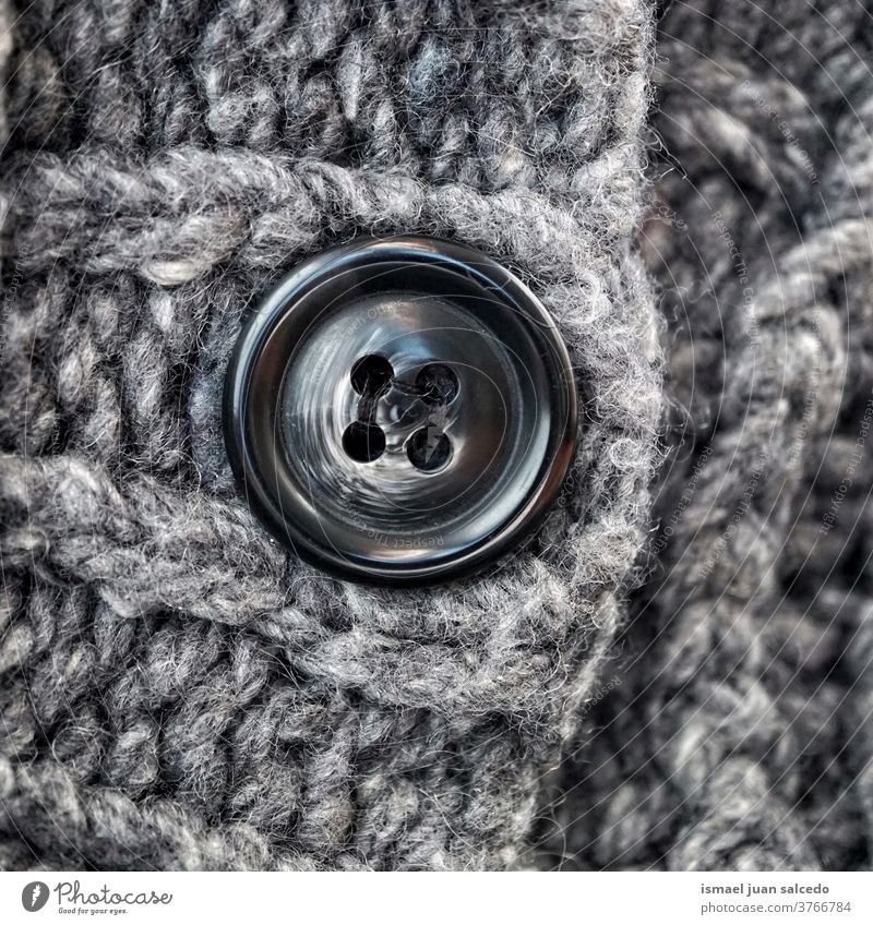 schwarzer Knopf in grauer Wolle, grauer Hintergrund Faser Gewebe Stoff texturiert abstrakt Muster Material Industrie Textil Design handgefertigt Detailaufnahme
