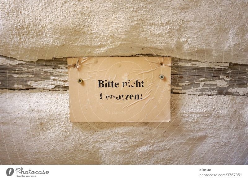 "Bitte nicht benutzen" steht unleserlich in schwarzer Druckschrift auf einem vergilbten Zettel, der an einem Holzbalken einer alten Wand befestigt ist. Verbot
