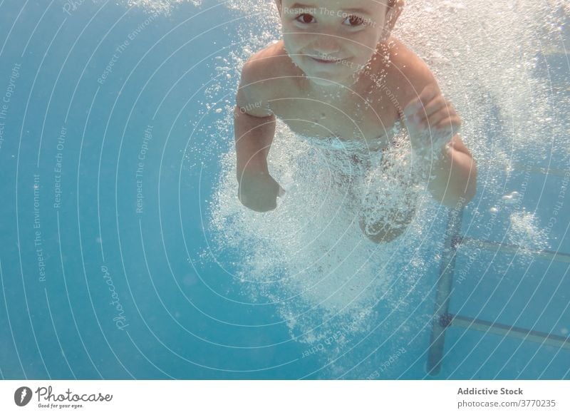Fröhlicher Junge im Schwimmbad schwimmen Pool Kind Sinkflug spielerisch Freude Kindheit Urlaub Sommer Spaß haben Wasser Erholung aqua heiter Badeanzug