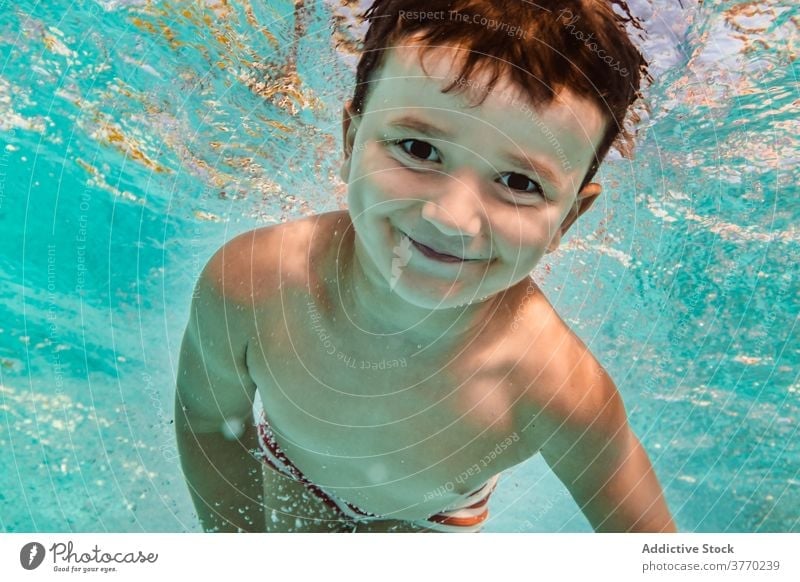 Fröhlicher Junge im Schwimmbad schwimmen Pool Kind Sinkflug spielerisch Freude Kindheit Urlaub Sommer Spaß haben Wasser Erholung aqua heiter Badeanzug