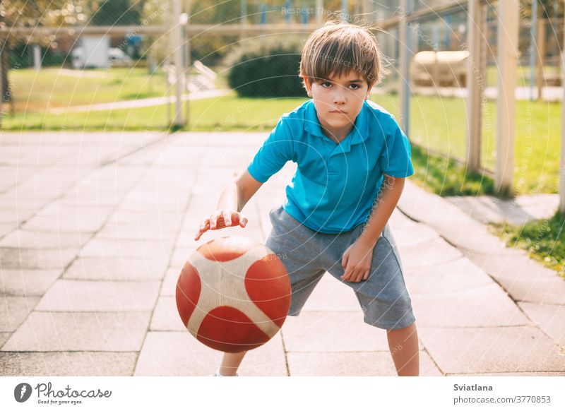 Ein fokussierter, süßer Athlet führt den Ball in einem Basketballspiel an. Ein Junge spielt nach der Schule Basketball. Sport, gesunde Lebensweise Dribbling