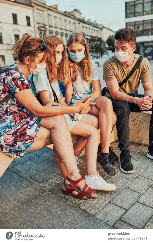 Junge Frauen verbringen Zeit miteinander, indem sie im Stadtzentrum sitzen und die Gesichtsmasken tragen, um eine Virusinfektion zu vermeiden Kaukasier Gespräch